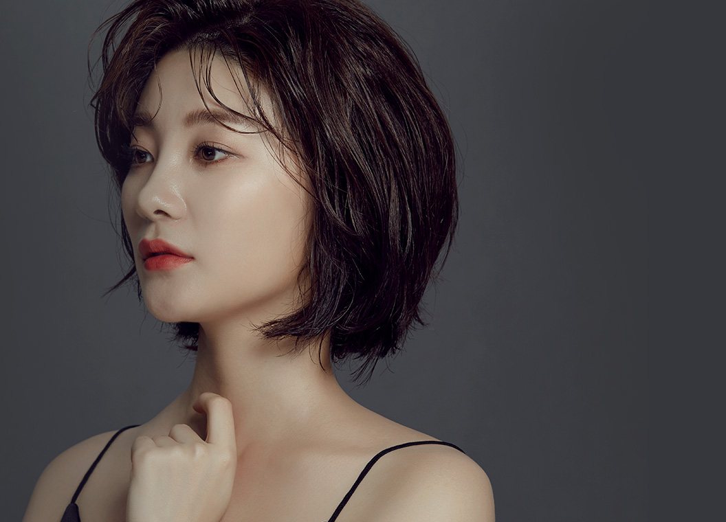짙은 회색 바탕 앞 단발 여성 모델 옆얼굴(코 라인)