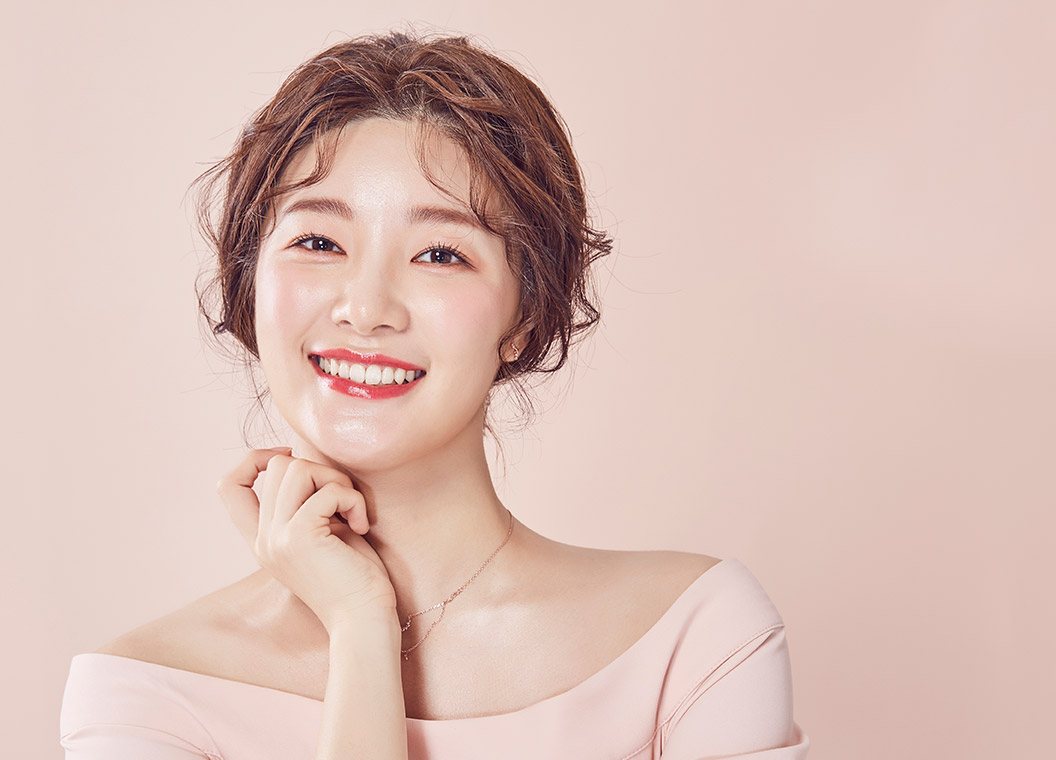 분홍 바탕 앞 활짝 웃는 여성 모델(턱선)